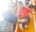 Aunt and nephew play on the slide at the park