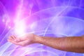 Aura phenomena. Man with flows of energy and lights around his hand against color background, closeup Royalty Free Stock Photo