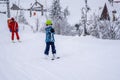 AURON, FRANCE - 01.01.2021: Professional ski instructor and child lifting on the ski drag lift rope to the mountain