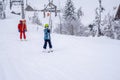 AURON, FRANCE - 01.01.2021: Professional ski instructor and child lifting on the ski drag lift rope to the mountain during