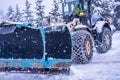 Auron, France 01.01.2021 Tractor removing snow from large snowbanks next to road on a ski resort in french Alps