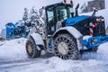 Auron, France 01.01.2021 Tractor removing snow from large snowbanks next to road on a ski resort in french Alps