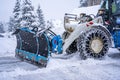 Auron, France 01.01.2021 Tractor removing snow from large snowbanks next to road on a ski resort in french Alps