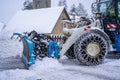 Auron, France 01.01.2021 Tractor removing snow from large snowbanks next to road on a ski resort in french Alps