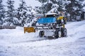 Auron, France 01.01.2021 Tractor removing snow from large snowbanks next to road on a ski resort in french Alps