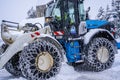 Auron, France 01.01.2021 Tractor removing snow from large snowbanks next to road on a ski resort in french Alps