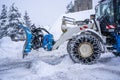 Auron, France 01.01.2021 Tractor removing snow from large snowbanks next to road on a ski resort in french Alps