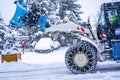 Auron, France 01.01.2021 Tractor removing snow from large snowbanks next to road on a ski resort in french Alps