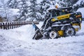 Auron, France - 01.01.2021: Wheel loader machine removing snow on a ski resort. Clearing the road from snow