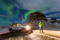 Aurora borealis above the man and car in Iceland. Green northern lights. Starry sky with polar lights.