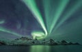 Aurora Borealis across a mountain range on Senja from HusÃÂ¸y, northern Norway