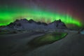 Aurora Borealis green reflection over the water at Stokksnes