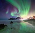 Aurora borealis on the Lofoten islands, Norway. Green northern lights above mountains and ocean shore. Night winter landscape with Royalty Free Stock Photo