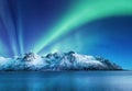 Aurora Borealis, Lofoten islands, Norway. Northen lights, mountains and reflection on the water. Winter landscape during polar lig