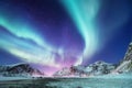 Aurora Borealis, Lofoten islands, Norway. Nothen light and reflection on the lake surface. Winter landscape at the night time. Royalty Free Stock Photo