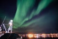 Aurora borealis, Northern lights over illuminated Reine town on coastline at Lofoten Islands Royalty Free Stock Photo