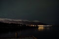 aurora borealis over snowy mountain and calm fjord in autumn