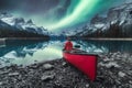 Aurora borealis over Spirit island with female traveler sitting on red canoe on Maligne Lake at Jasper national park Royalty Free Stock Photo