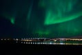 Aurora borealis over tromso city island, fjord and snowy mountain Royalty Free Stock Photo