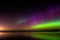 Aurora borealis with proton arc reflected over a lake