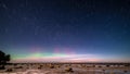 aurora borealis and stars in dark night over sea beach in winter