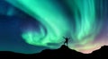 Aurora and silhouette of standing man with raised up arms on the mountain in Norway. Aurora borealis
