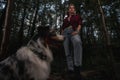 Aussie Australian Breed Dog With Beautiful Backpacker Woman Strolling And Hiking In Forest. Active Lifestyle With Pets