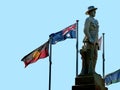 Aussie soldier keep silent sculpture stand against Australian flags isolated on blue sky Royalty Free Stock Photo