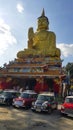 Austin Mini cooper and classic car parked in Thai temple with golden buddha statue and blue sky background.