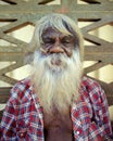 an aborigine with grey hair, long beard and checked shirt