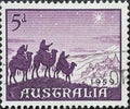 AUSTRALIA-CIRCA 1959 : A post stamp printed in Australia showing three camels with riders through the desert. Christmas 1959