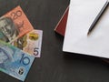 Australian banknotes, black pen and books