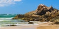 Australian coast with volcanic rocks on the shore, view from the beach to the horizon with blue water