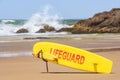 Australian coast, yellow lifeguard surfboard on the shore, guarded city beach with sand and rock shore on a sunny summer day