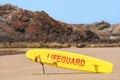 Australian coast, yellow lifeguard surfboard on the shore, guarded city beach with sand and rock shore on a sunny summer day