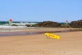 Australian coast, yellow lifeguard surfboard on the shore, guarded city beach with sand and rock shore on a sunny summer day
