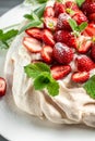 Australian dessert Pavlova cake meringue with whipped cream, fresh strawberrie and mint. Food recipe background. Close up