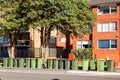 Australian garbage wheelie bins with colourful lids for general and green household waste lined up on the street kerbside for