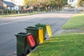 Australian garbage wheelie bins with colourful lids for recycling and general household waste lined up on the street kerbside