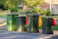 Australian garbage wheelie bins with colourful lids for recycling and general household waste lined up on the street kerbside