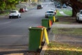 Australian garbage wheelie bins with colourful lids for recycling and general household waste lined up on the street kerbside for