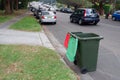 Australian garbage wheelie bins with colourful lids for recycling household waste and green garden waste lined up on the street