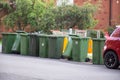 Australian garbage wheelie bins with colourful lids for recycling waste lined up on the street kerbside for council collection