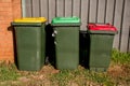 Australian garbage wheelie bins with red and yellow lids for general and recycling household waste and green lid for garden waste Royalty Free Stock Photo