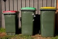 Australian garbage wheelie bins with red and yellow lids for general and recycling household waste and green lid for garden waste Royalty Free Stock Photo