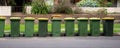 Australian garbage wheelie bins with yellow lids for recycling household waste lined up on the street kerbside