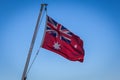 Australian Red Ensign flag on pole against blue sky background.