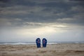 Australian thongs sticking upright in sand with dramatic storm clouds background. Australia day and waiting for rain concept