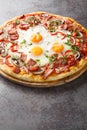 Australian traditional pizza with ham and eggs close-up on a wooden board. Vertical