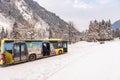 Austrian yellow Mercedes bus at bus stop. Snow, mountains and trees around. Styria, Austria, E